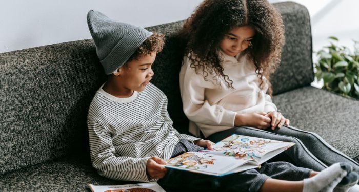 two kids reading childrens books on a couch